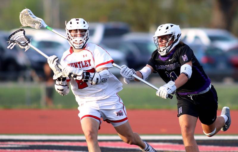 Huntley’s Nico Andrews, left, gets past Hampshire’s Wesley Davis in varsity lacrosse at Huntley Thursday night.