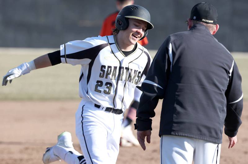 Sycamore's Kyle Hartmann is greeted by head coach Jason Cavanaugh as he rounds the bases after hitting his first of three home runs during their game against Harlem Monday, March 27, 2023, at the Sycamore Community Park.