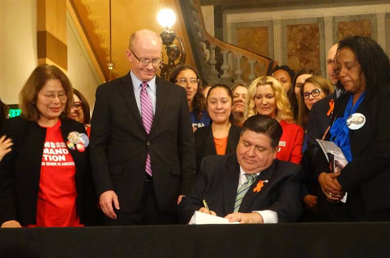 Gov. JB Pritzker signs a bill banning the sale and manufacture of assault weapons and high-capacity magazines on the Senate floor Monday. (Capitol News Illinois photo by Peter Hancock)