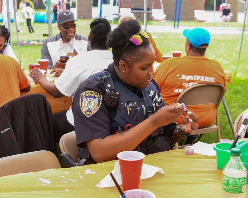 DeKalb police officer Chloe Albert paints a rock on Saturday, June 7, 2025, to support the Ezra Hill Jr. Memorial Foundation’s 5th annual rock painting event held at Tyler Elementary School in DeKalb. The foundation was created to memorialize the late DeKalb boy, shot and killed in 2019, and to spread awareness about gun violence.