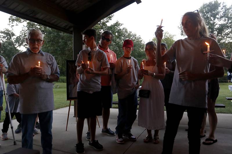 Peter Passuntino, left, says a prayer during a candlelight celebration for his grandson, Riely Teuerle on Thursday, August 11, 2022, at Towne Park, 100 Jefferson Street in Algonquin. Teuerle was killed in a car crash in Lake in the Hills on Tuesday. Over 100 family members and friends gathered at the park to remember and celebrate Teuerle’s life.