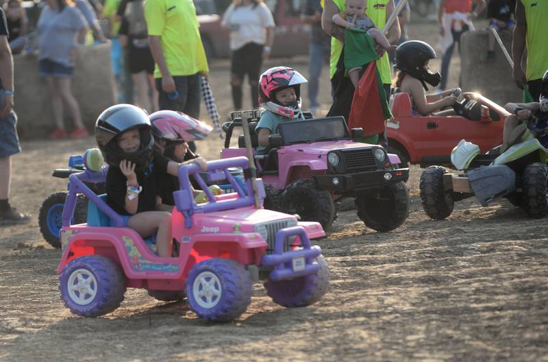 Brinley Blatter, 3, of Oregon, looks to the crowd as she rides with Memphis Mongan, 5, also of Oregon, in the kids power wagon "Demo Derby" before the start of the real demolition derby at the Ogle County Fair on Saturday, Aug. 2, 2025.