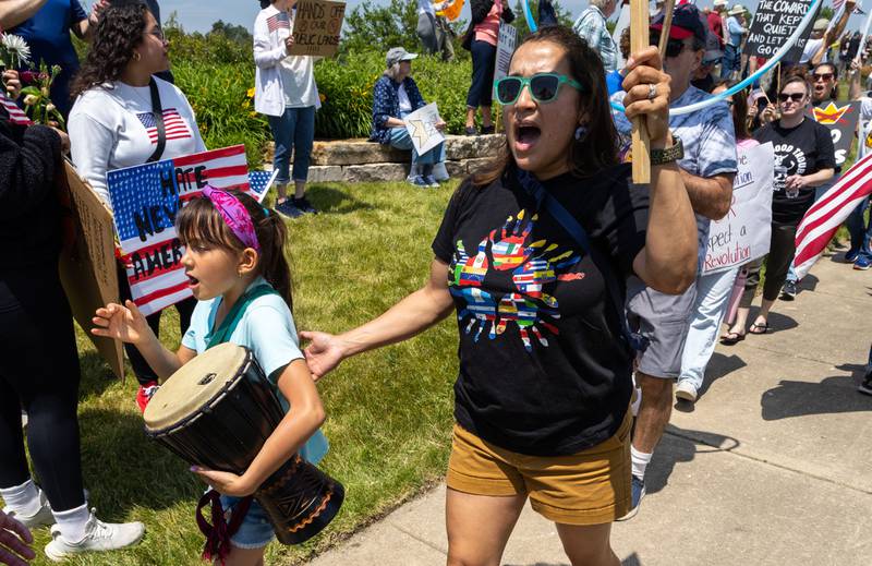 Jenny Fearday of Aurora, right, chants while her daughter Rita Fearday, 7, bangs on a drum during a “No Kings Day” Protest against President Donald Trump’s policies along South Randall Road in Geneva on Saturday, June 14, 2025.