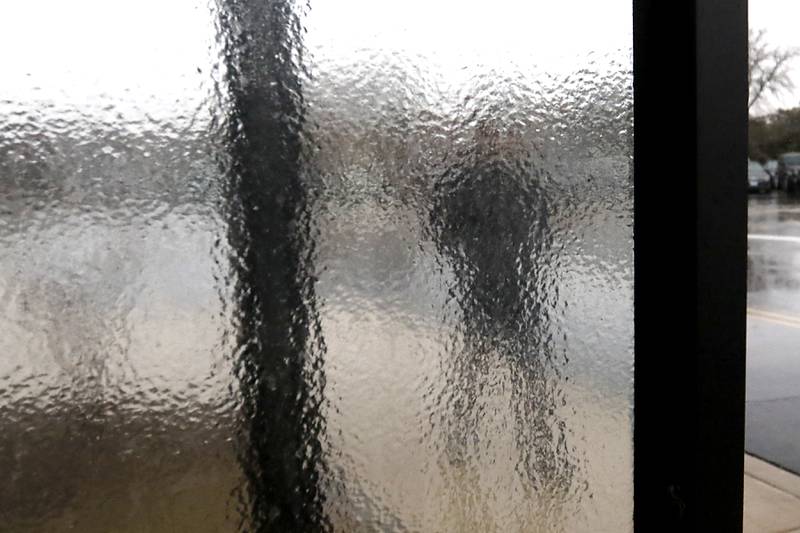 A man walks out of the McHenry County courthouse in Woodstock as ice covers the window a bus stop on Wednesday, Feb. 22, 2023, as a winter storm that produced rain, sleet, freezing rain, and ice moved through McHenry County.