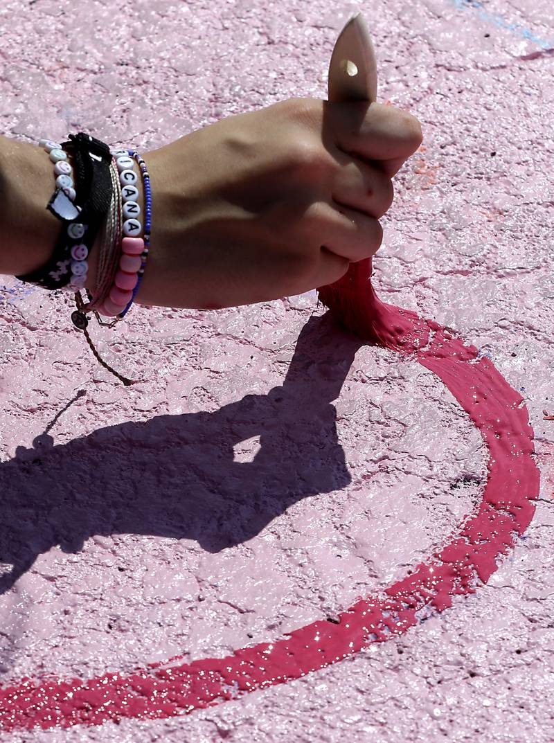 Marian Central Catholic High School junior Tessa Weber paints a heart on Tuesday, Aug. 13, 2024, while painting her parking spot at the Woodstock school.