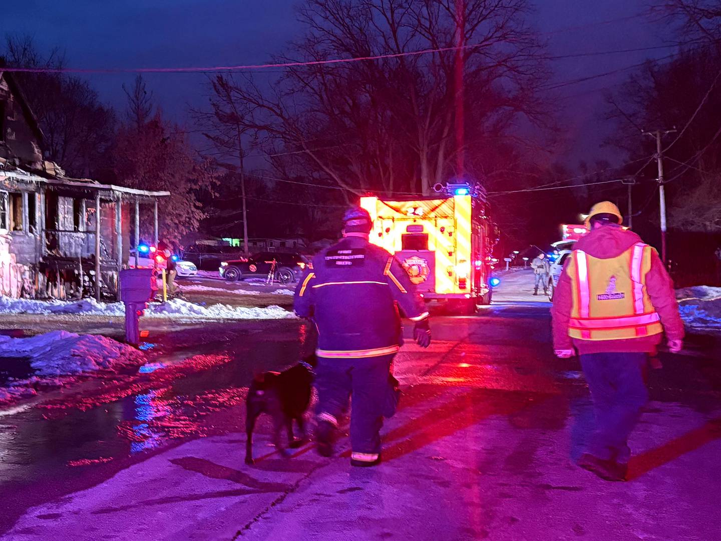 Fire personnel and a dog walk through the scene of a fatal fire on Dec. 19, 2025, near Spring Grove.
