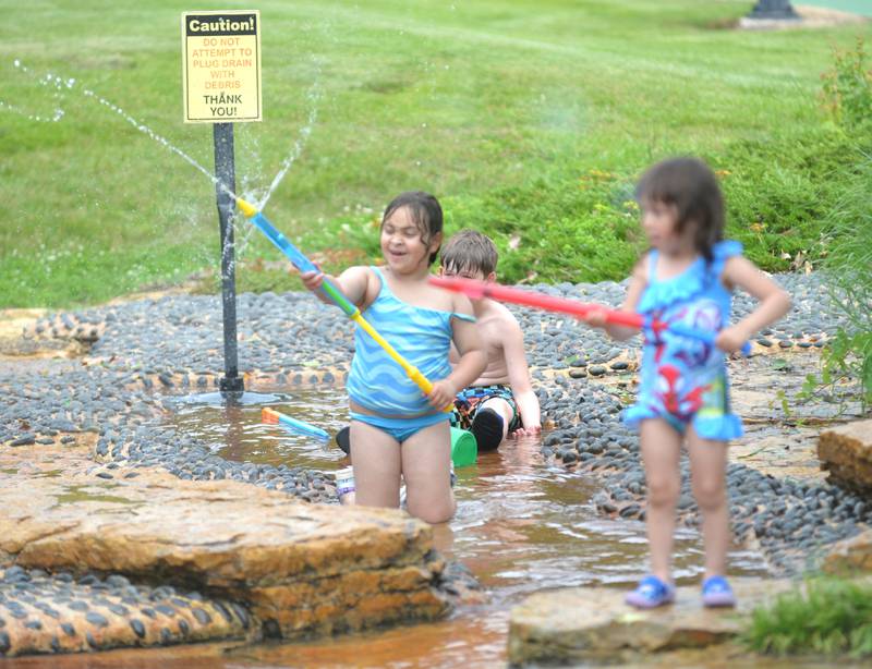 Maelynn Morehead, 6, of Oregon, sprays water into the air at the Oregon Park District's Splash Pad at Oregon Park West on Tuesday, June 4, 2024. The park district hosted a pop-up and play event during the afternoon complete with a bubble machine and various types of water guns. The Splash Pad is located next to the shelter and playground at Park West and no admission s charged.
