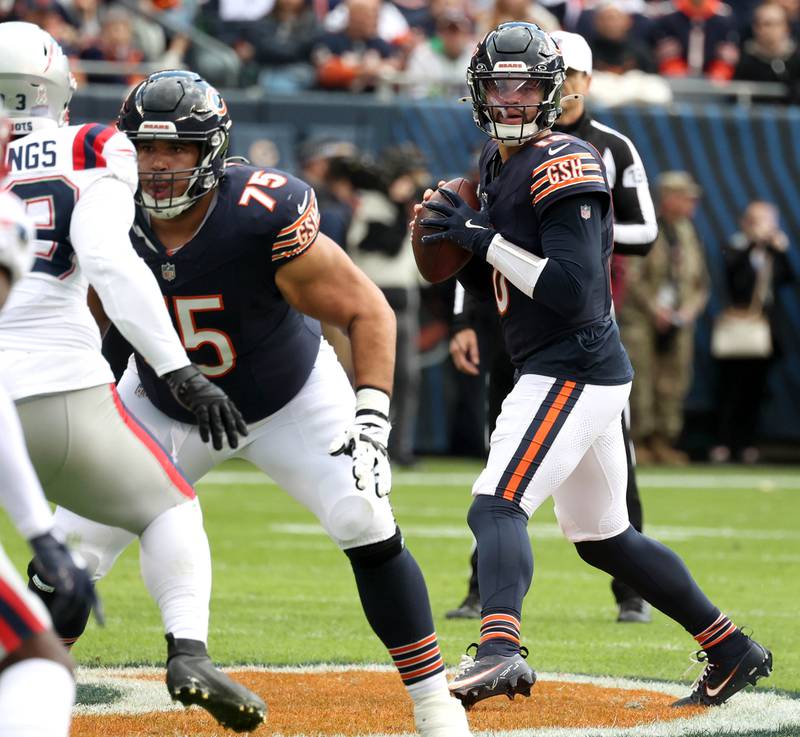 Chicago Bears quarterback Caleb Williams looks for a receiver behind the blocking of Chicago Bears offensive tackle Larry Borom during their game against New England Sunday, Nov. 10, 2024, at Soldier Field in Chicago.