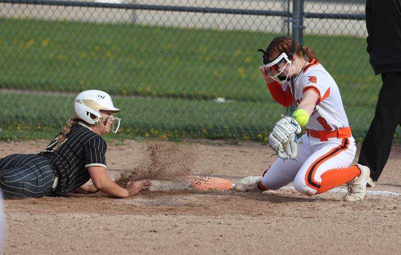 Sycamore's Addison Armstrong dives back into first as DeKalb's Cassidy Cavazos prevents the throw from getting into the outfield Friday, May 2, 2025, during their game at DeKalb High School.