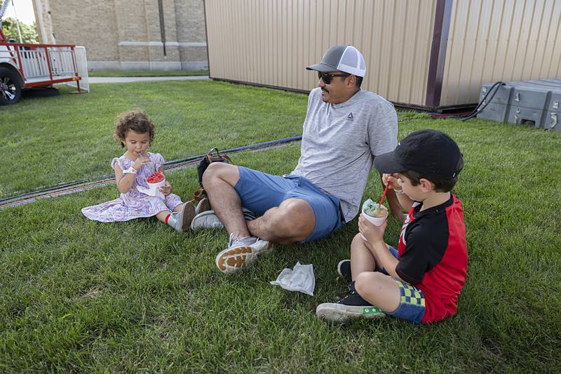 Ricky Gonzalez of Dixon sits with kids Mila, 3, and Isco, 5, as they all take a break in the shade with a cool drink Wednesday, July 3, 2024 at the Petunia Fest carnival.