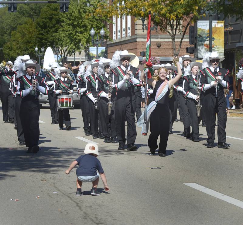 This youngster gathers some candy treats as the LaSalle Peru Marching Cavaliers parade down LaSalle St Sunday during the Fall Festival Parade in Ottawa.