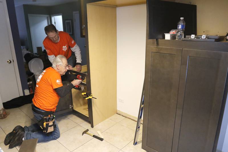 Tom Powers (kneeling) and Jerry Webb, from Home Depot, install new cabinets in veteran Craig Taylor's home on Thursday Jan. 16, 2025. The kitchen remodel for Taylor is part of the 30 Days for 30 Vets program.
