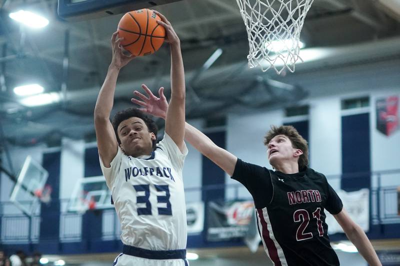 Oswego East's Michael Rembert (33) rebounds the ball against Plainfield North's Joseph Charbonneau (21) during a basketball game at Oswego East High School on Friday, Dec. 6, 2024.