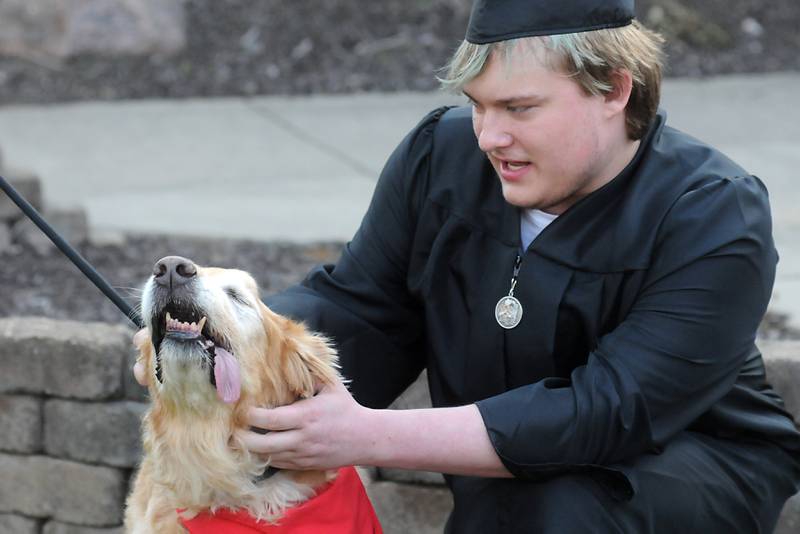 Skyler Cochran pets Henry, a therapy dog that comes to the school with teacher Anne Whitney-Tubridy, on Thursday, May 12, 2022, during the Haber Oaks Campus graduation celebration in the courtyard of Crystal Lake South High School.