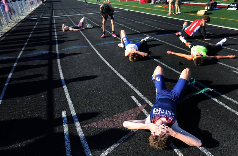Runners lie on the track after finishing the 3200 meter run during the IHSA Class 2A Richmond-Burton Sectional Boys Track and Field Meet on Wednesday, May 20, 2026, at Richmond-Burton High School.