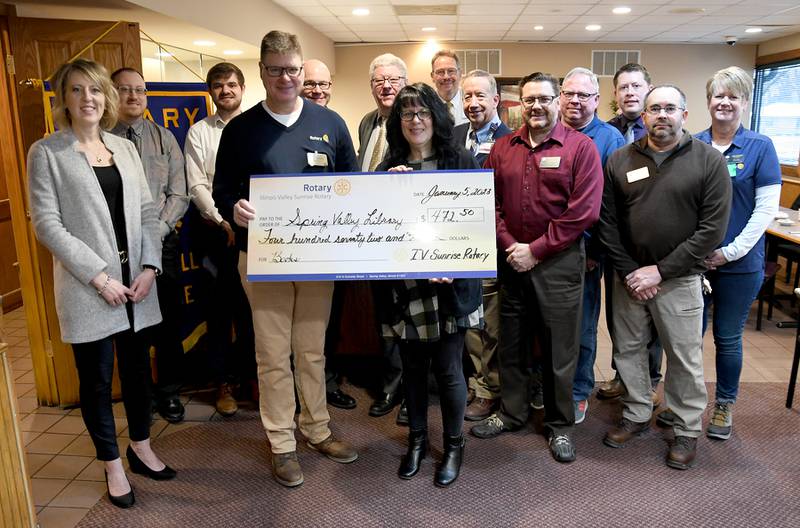 Richard Mautino Memorial Library Director Terri Sangston accepts a $472 check from the Illinois Valley Sunrise Rotary.