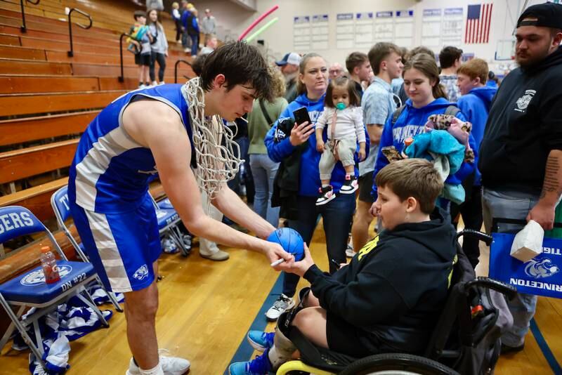 Princeton senior Noah LaPorte autographs a mini-basketball for Shane Shofner following Friday's regional championship victory over Seneca.