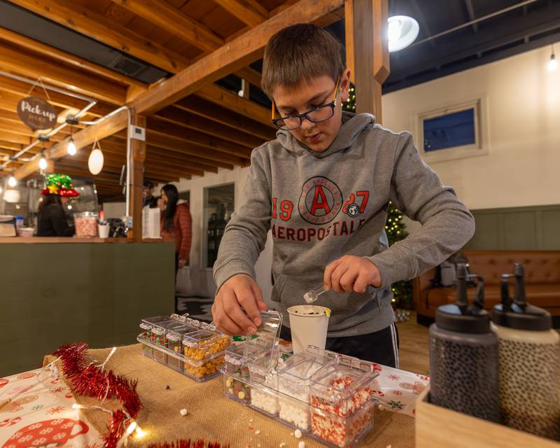 Aj Widolff drops marshmallows into hot chocolate on Sunday, December 14, 2025 at The Coffee Barn in Mendota.