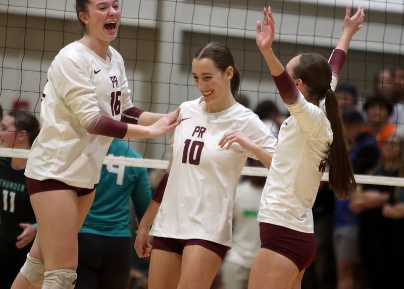 From left, Prairie Ridge’s Adeline Grider, Addison Smith and Erin Riley celebrate during a win over Woodstock North in IHSA Class 3A Sectional semifinal volleyball action on Tuesday, Nov. 5, 2024, at  Crystal Lake South High School  in Crystal Lake.