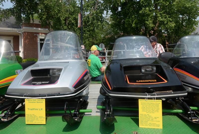 Dan Dykstra (center) chats with his brother as he sits on his trailer that nine of his  vintage snowmobiles on display at the Milledgeville car show on Sunday, June 4. Temperatures neared 90 degrees during the event, but the snowmobiles, which were manufactured between 1974 and 1984, didn't seem to care.