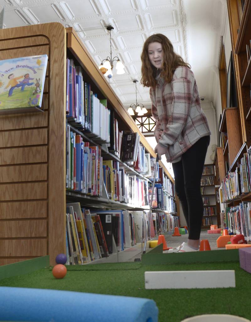 Laynee Lucas washes her ball roll towards the hole Saturday during the Carnegie Challenge Mini Golf FUN-Raiser at the Streator Public Library.