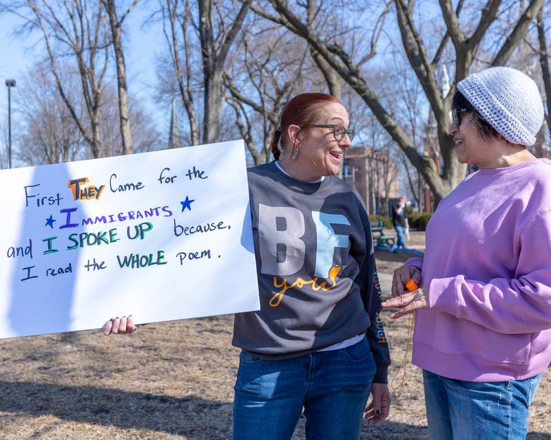 Murri Briel speaks to protester while holding sign at the 'Pretti good time for a Protest' on Feb. 15, 2026 at Washington Square Park in Ottawa.