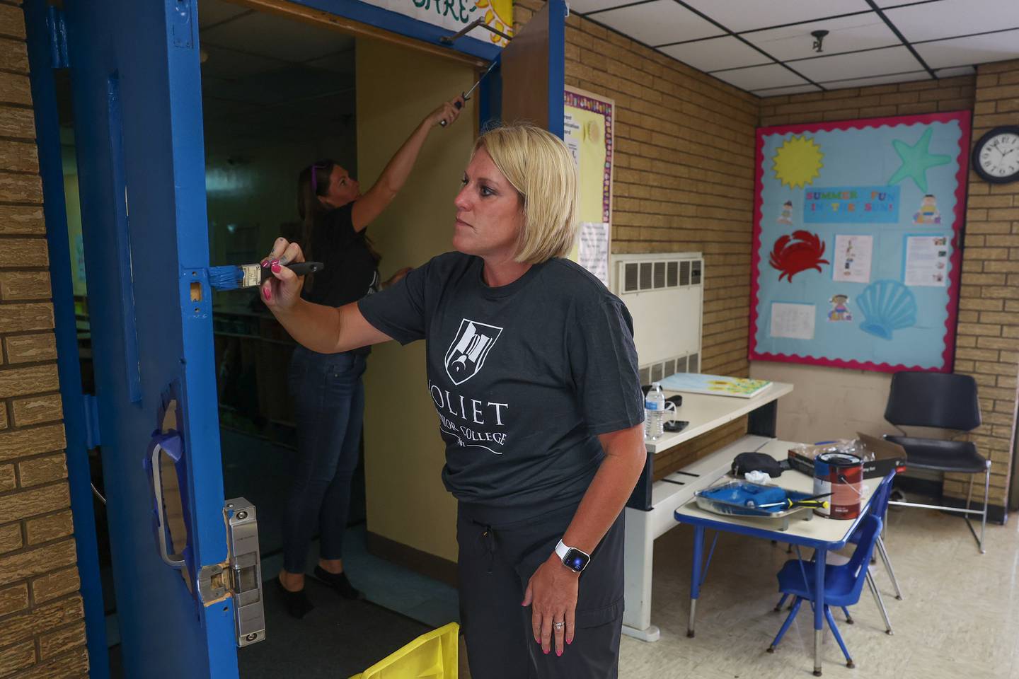 Amanda Quinn, with the JJC Foundation, foreground, and Jen Davis, of alumni relations, paint the doors at the Spanish Community Center on Wednesday, Aug. 16, 2023 in Joliet.