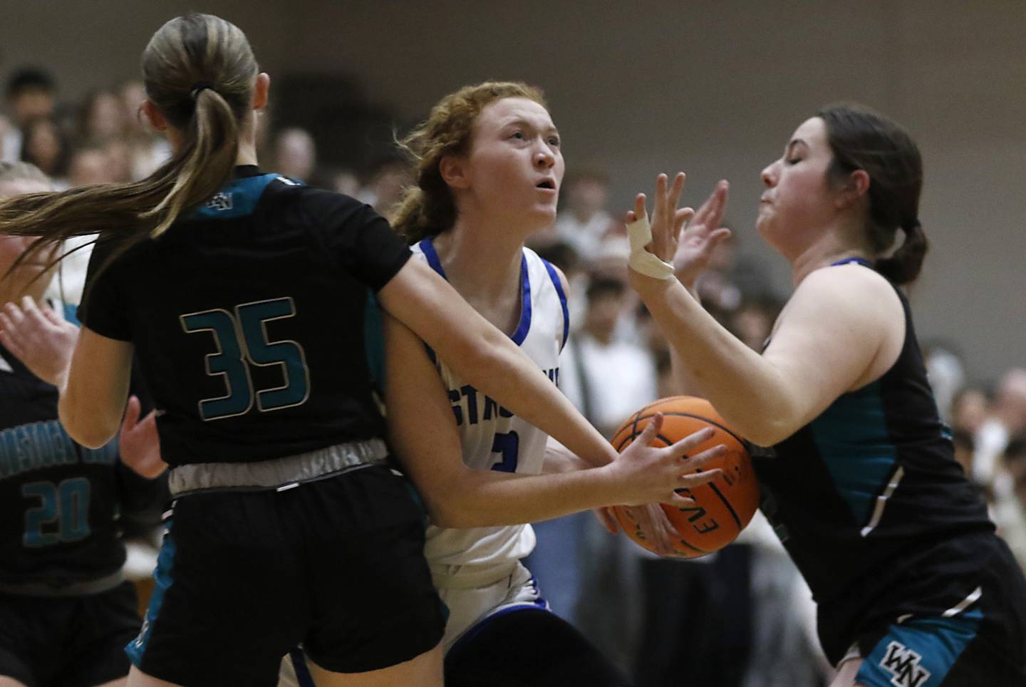 Woodstock's Keira Bogott drives to the basket between Woodstock North's Adelyn Crabill (left) and Brenna McConnell (right) during a Kishwaukee River Conference basketball game on Friday, Jan. 10, 2025, at Woodstock High School.
