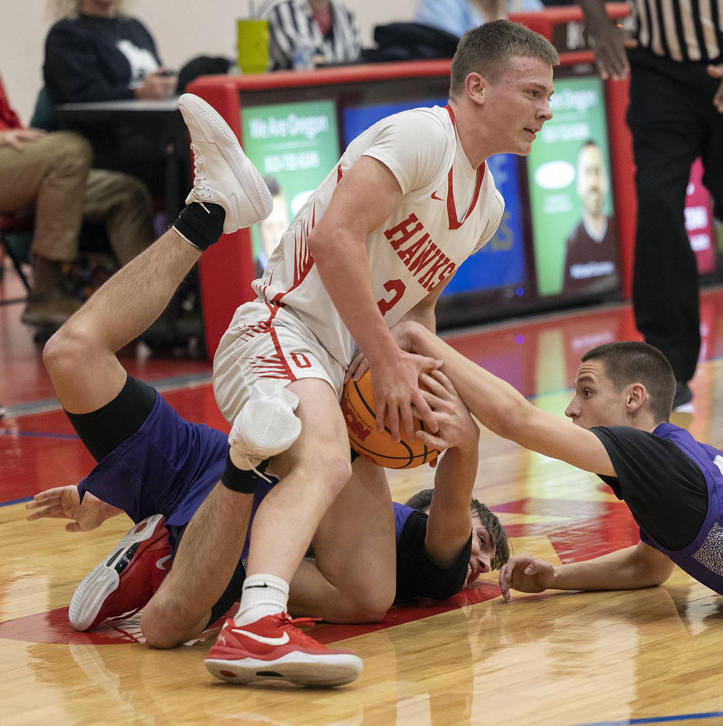 Oregon’s Cooper Johnson wrestles Dixon’s Brady Feit (left) and Dixon’s Cullen Shaner for a loose ball Tuesday, Feb. 4, 2025, in Oregon.