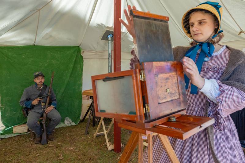 Reenactor Xander Mezo holds still for an eight second exposure as photographer Louisa Olsen prepares the wet plate camera for the portrait at The Blue and Gray Civil War reenactment at City County Park on October 10, 2025 in Princeton.