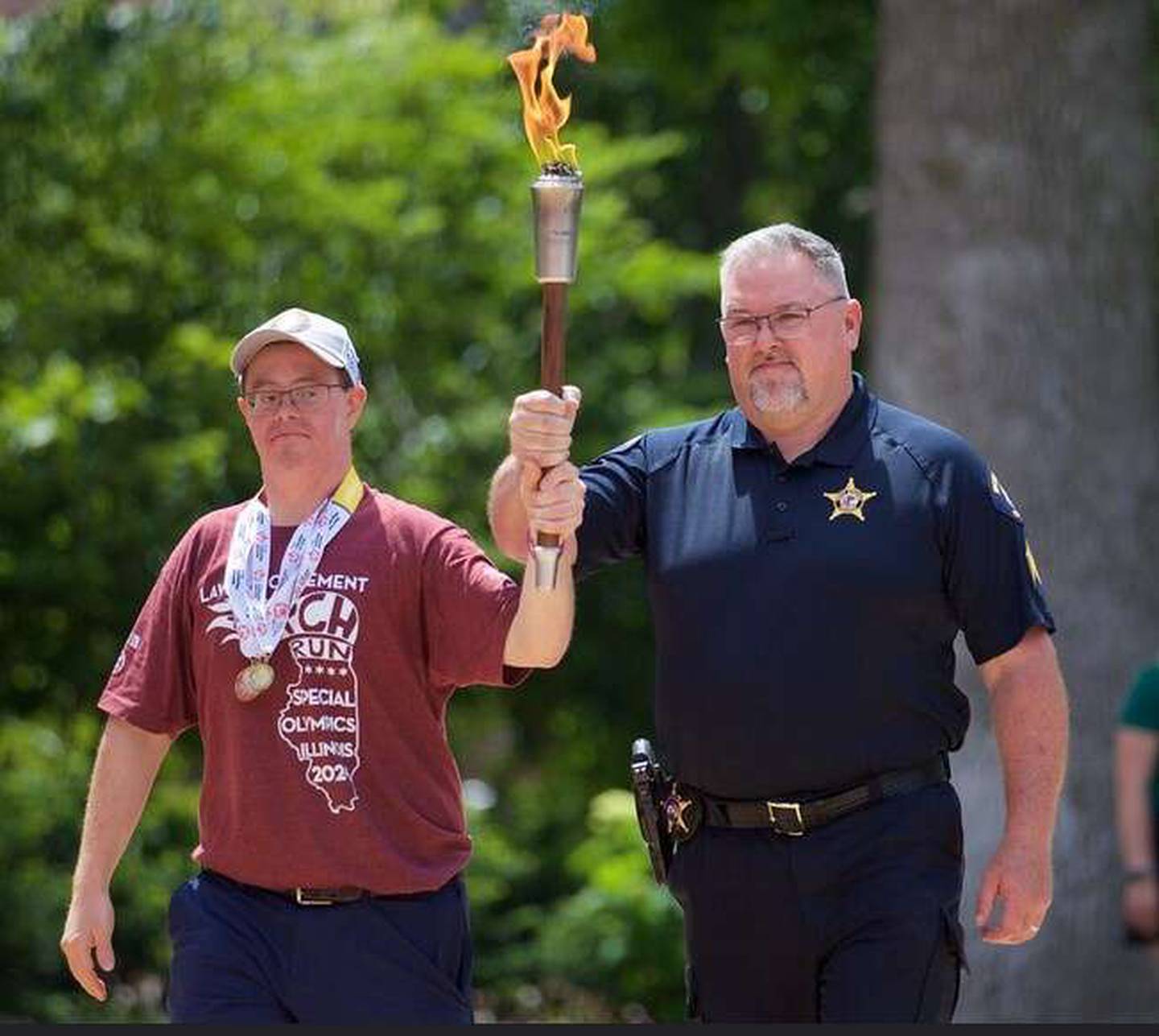 Athlete Jonathan Mies, left, and West Chicago Police Detective Sgt. Robbi Peterson carried the Flame of Hope to light the cauldron at the 2024 Special Olympics Illinois Summer Games Pep Rally in Springfield.