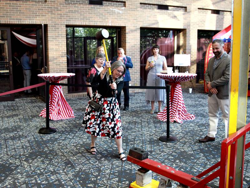 Rose Canfield swings a giant hammer while playing carnival games during the 56th Annual Charlemagne Awards Dinner hosted by the St. Charles Chamber of Commerce at the Q Center in St. Charles on Friday, May 17, 2024.