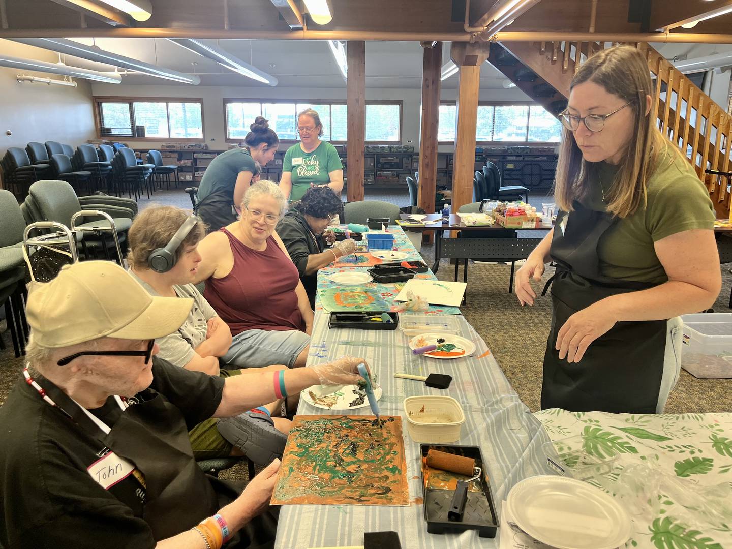 Volunteer art instructors help participants apply paint to their canvases during the 'Art for Everyone' class at the Yorkville Public Library.