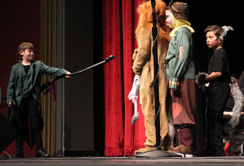 The Wizard of Oz (Kaelynn Johnson), far left, accepts the late Wicked Witch's broom in return for granting the wishes of the Tin Man (Braison Kelly), Cowardly Lion (Bentley Lurz), Scarecrow (Jaxton Anderson), Dorothy Gale (Karsyn Stewart) and Toto (Leo Gonzalez) on Friday, March 22, 2024, during the Streator Elementary Schools production of "The Wizard of Oz – Youth Edition" at Streator High School.