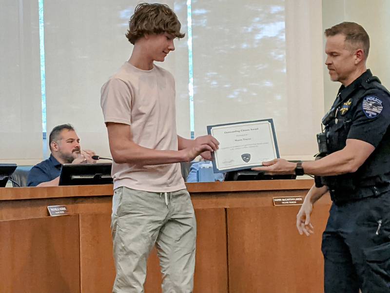 Oswego Police Chief Jason Bastin, right, presents Oswego East High School student Mason Trayser, left, with the  Oswego Police Department’s Outstanding Citizen Award during the June 10 Oswego Village Board meeting. Trayser received the award for saving a fellow student from drowning in the school's swimming pool.