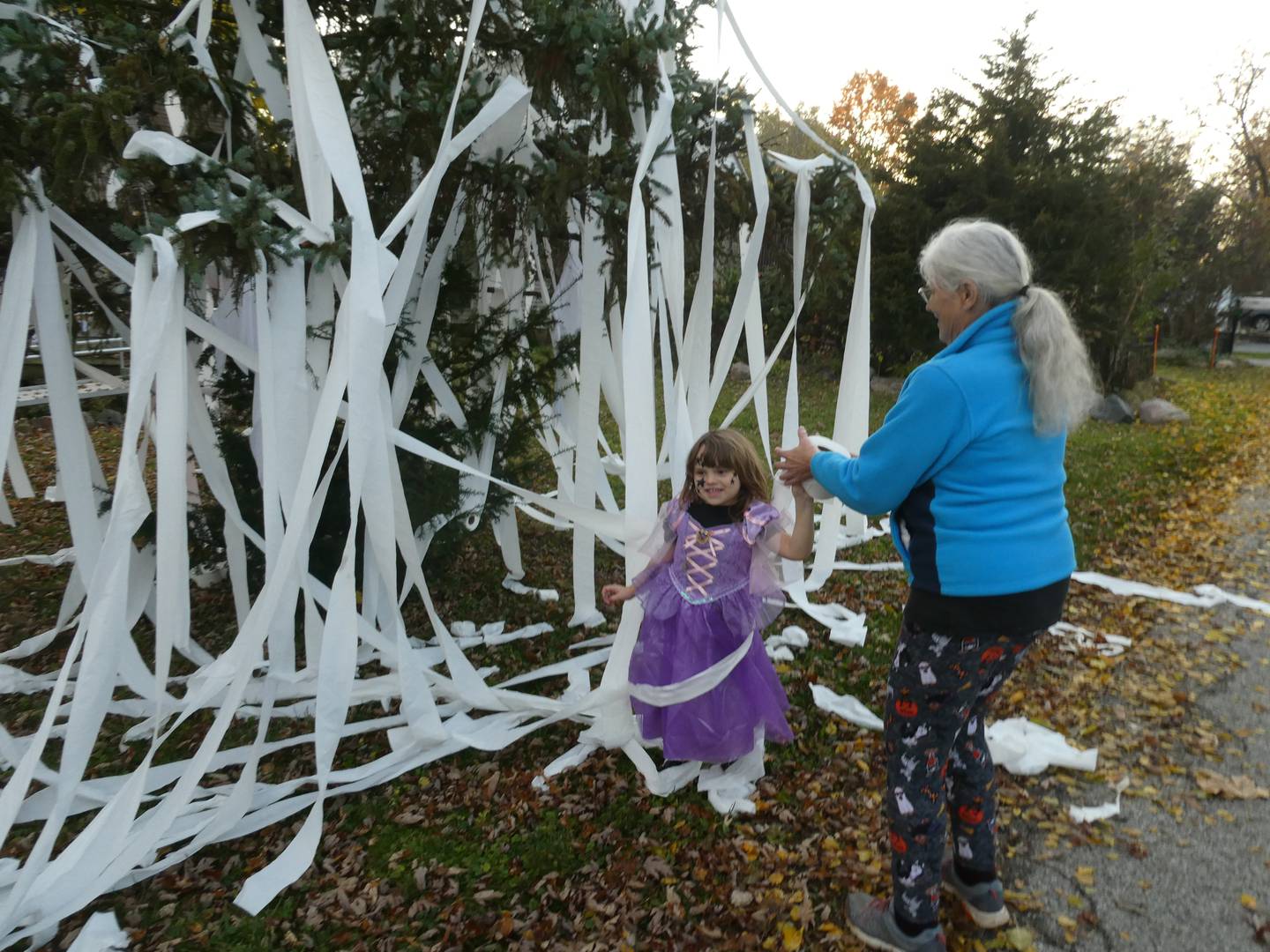 McCullom Lake trick-or-treaters Mary Hansen and her granddaughter Christa explore a teepeed tree in Kerry Neff's front yard on Monday, Oct. 31, 2022, as part of an annual Halloween tradition.