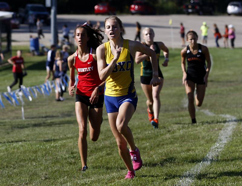 Johnsburg’s Jolene Cashmore races with Huntley’s Brittney Burak during the girls race of the McHenry County Cross Country Meet Saturday, August 27, 2022, at Emricson Park in Woodstock.