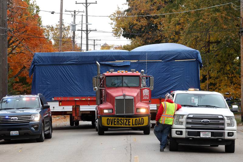 A house has to make a brief stop so a car can be moved out of the way Tuesday, Oct. 22, 2024, as it makes its way down Pleasant Street in DeKalb. The home was moved from the DeKalb County History Center property in Sycamore to its new location on Pleasant Street by Devooght House Movers and Habitat For Humanity for Heaven Allen and her son who will be living in the home when it is completed.