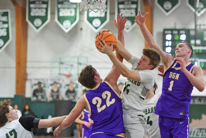 Glenbard West’s Finn Sheeley  grabs a rebound from between Downers Grove North’s Jacob Vroman (22) and Colin Doyle (1) during a game on January 23, 2026 at Glenbard West High School in Glen Ellyn.