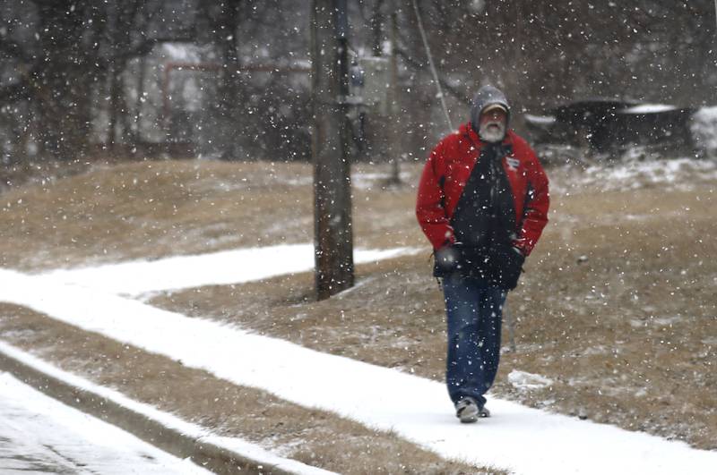A man walks along a snow covered sidewalk on Wednesday, Feb. 12, 2025, in Johnsburg as a winter storm starts to bring heavy snow to the McHenry County area.
