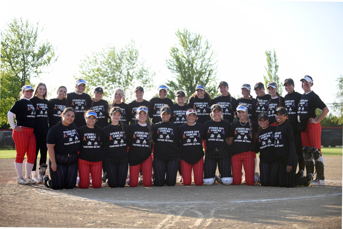 The Bradley-Bourbonnais and Bishop McNamara softball teams pose in their shirts for their Strikeout Cancer Night at their All-City game hosted by Bradley-Bourbonnais Thursday, May 8, 2025.