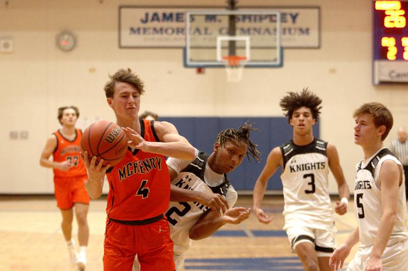 McHenry’s Dylan Hurckes (4) battles Kaneland’s Isaiah Gipson (2) in Hoops for Healing basketball tournament championship game action at Woodstock Wednesday.