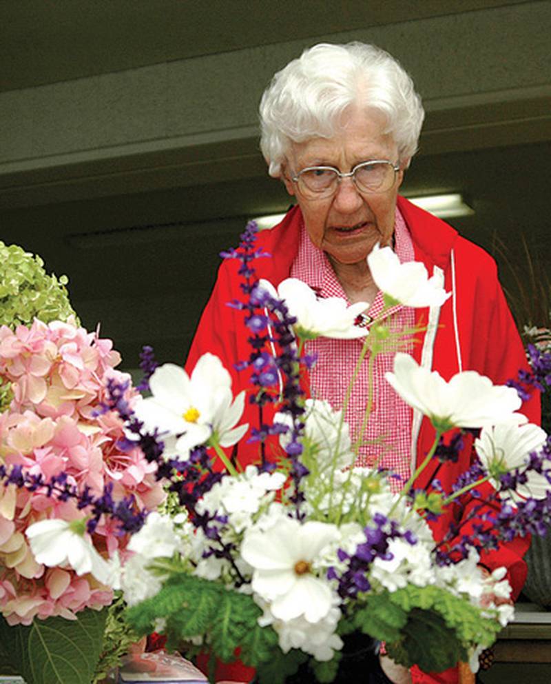 Polo Women’s Garden Club member Annabelle Cunningham examines a floral arrangement during the flower show Aug. 1.