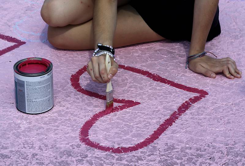 Marian Central Catholic High School junior Tessa Weber paints a heart on Tuesday, Aug. 13, 2024, while painting her parking spot at the Woodstock school.