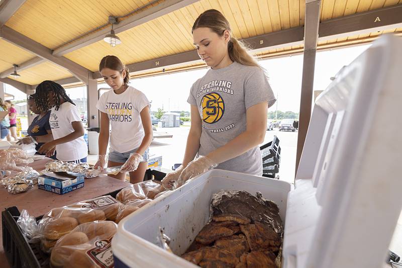 Macie Lofgren (left), and Natalie Eddinger put together pork chop sandwiches Monday, July 22, 2024 at the Rotary Broil and Boil Lunch. The two are volunteers as part of the Sterling basketball team.