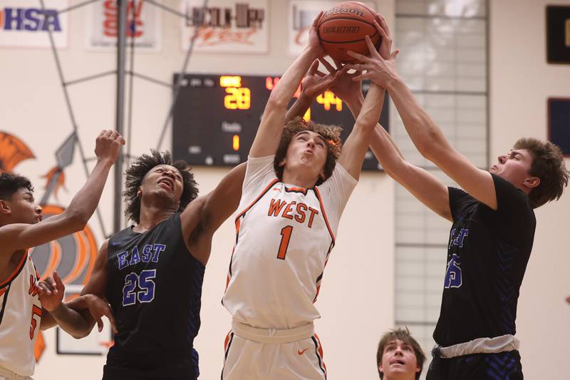 Lincoln-Way West’s Jacob Bereza battles Lincoln-Way East’s George Bellevue, 25, and Brayden Lovell, 15, for the rebound.