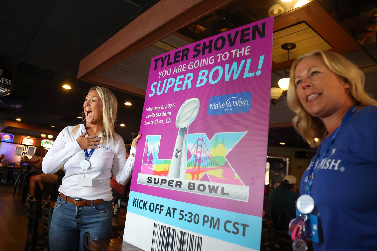 Make-A-Wish Illinois volunteers Gina Cordes, left, and Lisa Holt surprise Tyler Shoven, of Clifton, with a trip to the Super Bowl using a giant ticket last week as his family dined at Sammy's Pizza in Bourbonnais.