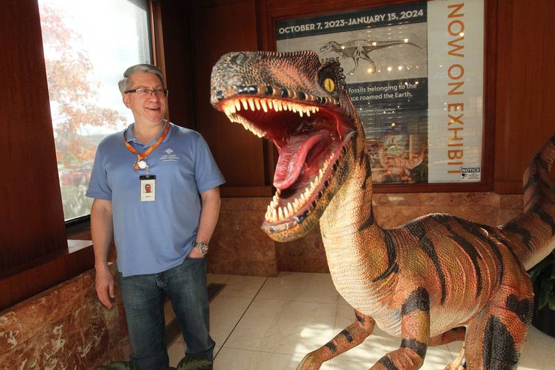 John Adams, of Mundelein, visitor's services clerk, talks about the feathered Velociraptor on display at the entrance to the Dinosaurs: Fossils Exposed exhibit at the Dunn Museum on October 28th in Libertyville. The exhibit is sponsored by the Preservation Foundation of the Lake County Forest Preserves and runs through January 15, 2024.
Photo by Candace H. Johnson for Shaw Local News Network