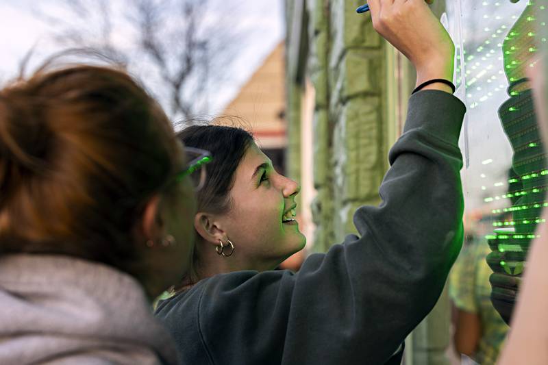 Katrina Lecaj is all smiles as she works on decorating a window at Froggy’s in downtown Rock Falls Monday, Nov. 6, 2023 for the volleyball team’s trip to state.