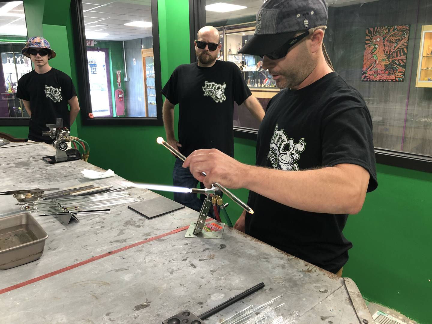 Instructors Kyle Myers, Nick Pruitt, and Tom Schodtlur at Otto’s in McHenry, showing students how to use an oxygen and propane flame to mold glass on July 18, 2022.
